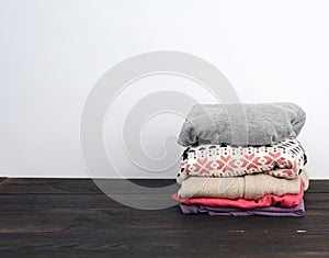 Stack of various folded clothes on a wooden table, white background