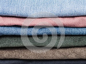 Stack of various jeans and corduroy slacks photo