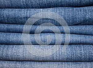 stack of various shades of blue jeans as background