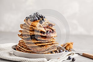 Stack vegan blueberry pancakes with peanut butter and syrup.