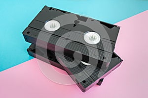 Stack of 3 VHS tapes on pink and blue background. photo