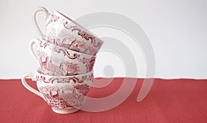 Stack of vintage tea cups on red table