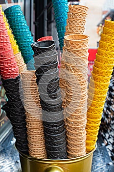 Stack of waffle cones of different colors, pink, black and brown for ice cream and yoghurt