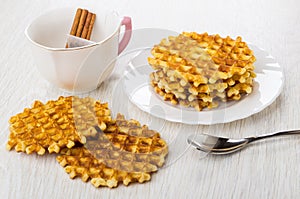 Stack of waffles in plate. Cup with cinnamon, tea bag, spoon