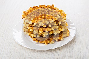 Stack of waffles in plate on wooden table