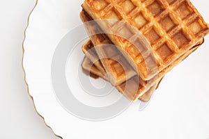 Stack of waffles on white plate with white background. Top view