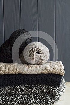 Stack of warm clothes from knitted knitwear over grey wooden background