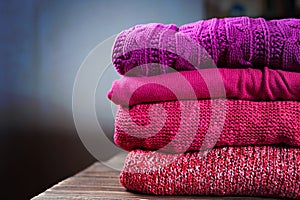 Stack of warm knitting clothing lying on a wooden table
