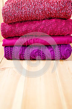 Stack of warm pink, purple and violet cozy sweaters