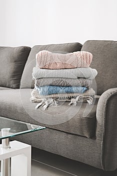 Stack of warm sweaters on gray sofa bed in the living room