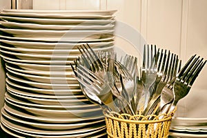 A stack of washed dishes and forks in the kitchen