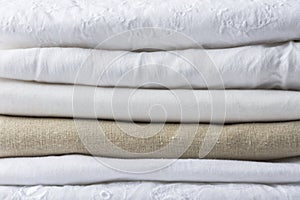 Stack of white and beige pure organic cotton and linen folded fabric. Clothing laundry home textile sewing concept