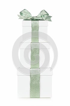 Stack of white Christmas gift boxes with frosty green bow and ribbon isolated on white