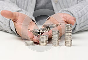 Stack of white coins and female hands are holding a pile of coins. Poverty, budget planning. Subsidy and low salary