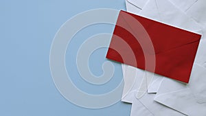 A stack of white envelopes with a red envelope on top. Blue background with copy space