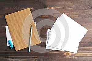 Stack of white envelopes on a wooden background. A blue handle and a sheet of kraft paper. Flat lay, top view