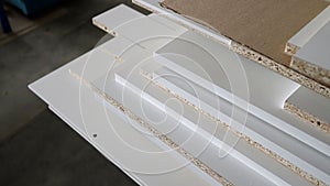 A stack of white MDF panels lies on the floor. Material for the production of furniture, panels. Veneered chipboard in a