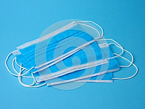 Stack of white medical textile individual masks with elastic bands for protection against virus