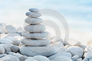 Stack of white pebbles stone against sea background for spa, balance, meditation and zen theme.