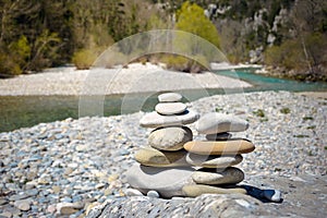 Stack of white pebbles stone against blue mountain stream background