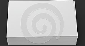 A stack of white, rectangular sheets of paper rests on a dark gray surface. The paper