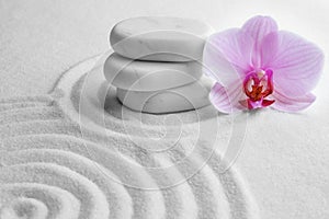 Stack of white stones and flower on sand with pattern. Zen, meditation, harmony