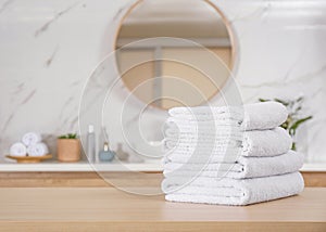Stack of white towels on wooden table in bathroom