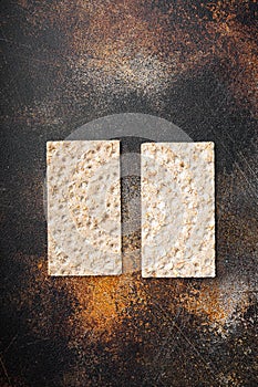 Stack of wholegrain crispy bread with sunflower, chia and sesames seeds, on old dark rustic table background, top view flat lay,