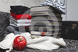 Stack of winter clothes and books with glossy edge