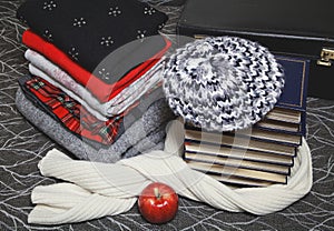 Stack of winter clothes and books with gold edge