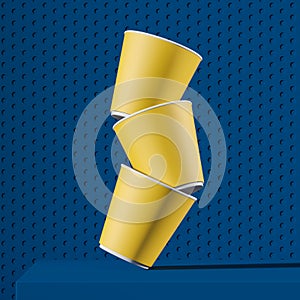 Stack of yellow paper cups falling on blue table