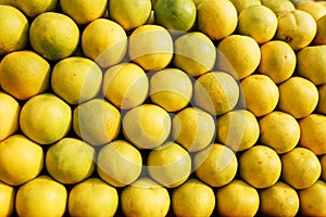 A stack of yellow ripe and sweet lines on the whole screen on the market. Lime and lemons background. Fresh organic lemons and