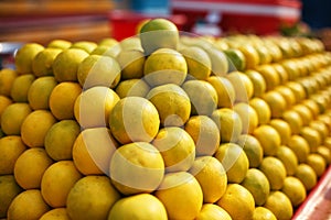 A stack of yellow ripe and sweet lines on the whole screen on the market. Lime and lemons background. Fresh organic lemons and