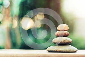 Stack of zen stones on ground with blurred nature background.