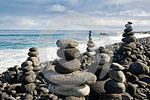 Stack of zen stones over water and blue sky.