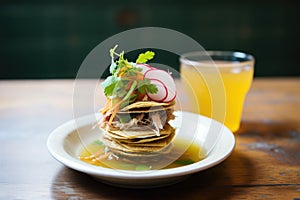 stacked birria tacos with consomme cup on the side