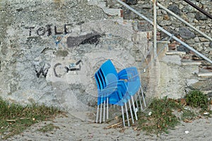 Stacked blue chairs are tied with chain and padlock to the railing of a staircase