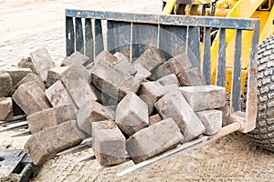 Stacked bricks on scoop of excavator