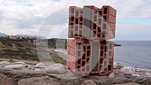Stacked bricks with thermal insulation foam on rocky coast against ocean showcase sustainable building, energy-saving