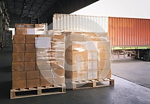 Stacked of cardboard on pallet rack. Cargo trailer truck parked loading at dock warehouse. Cargo shipment. Freight truck transport