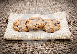 Stacked chocolate chip cookies on brown napkin over gunny backg