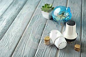 Stacked coins, piggy bank and thermostats on wooden table. Heating saving concept