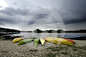 Stacked of the colorful canoes near the lake