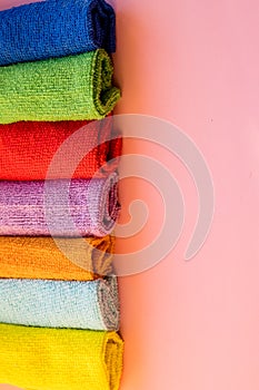 Stacked colorful microfiber cleaning cloths on a pink background. Colorful, dry microfiber cloths for different surfaces