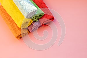 Stacked colorful microfiber cleaning cloths on a pink background. Colorful, dry microfiber cloths for different surfaces