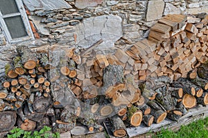 Stacked firewood wood lumber timber stack logs and trunks pile by a historic cottage cottage
