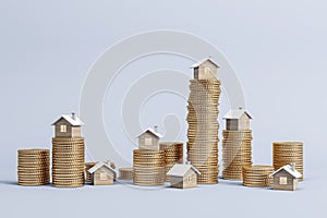 Stacked golden coins with small houses on light backdrop with mock up place for advertisement.