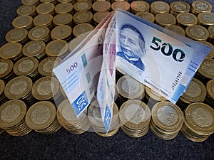 stacked mexican coins of ten pesos and banknotes of 500 pesos