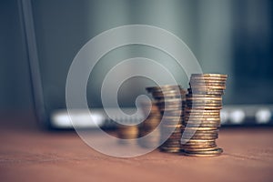 Stacked money coins and laptop computer