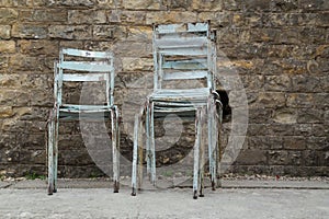 Stacked Old Metal Chairs against Grunge Brick Wall